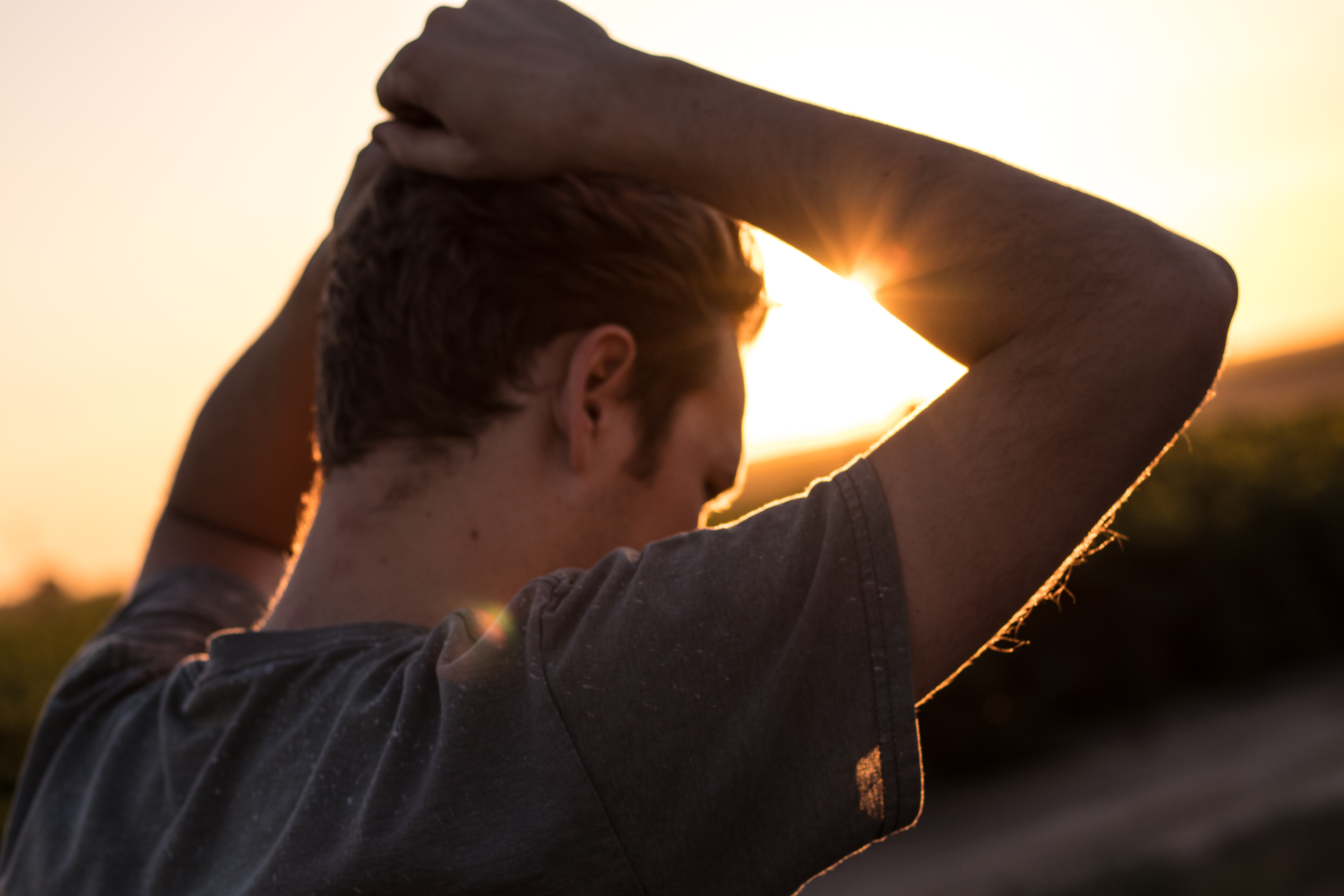 En mand tager sig til hovedet, mens solen går ned